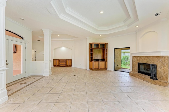 unfurnished living room featuring a raised ceiling, light tile patterned flooring, ornamental molding, and a tiled fireplace