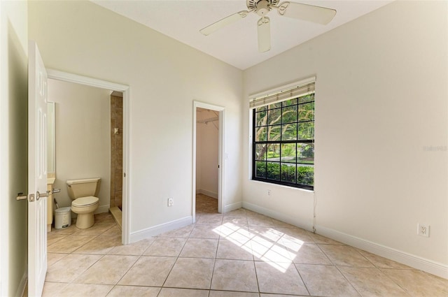 unfurnished bedroom featuring ceiling fan, light tile patterned floors, a closet, a walk in closet, and ensuite bath