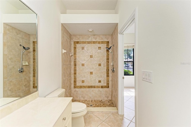 bathroom with vanity, a tile shower, tile patterned floors, and toilet