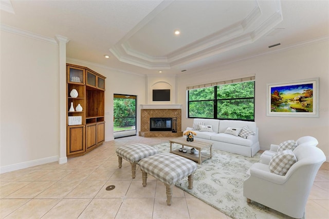 tiled living room featuring a raised ceiling, crown molding, and a tiled fireplace