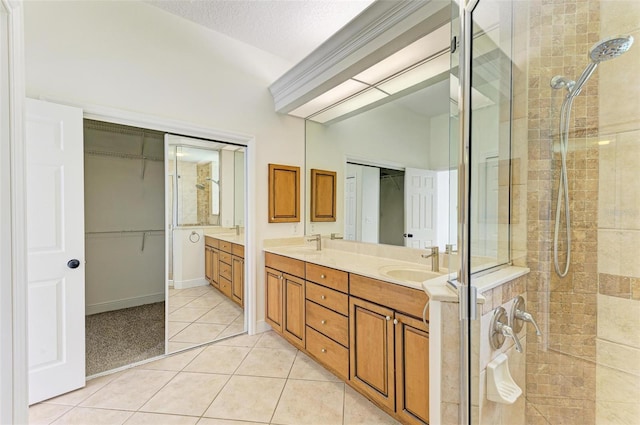 bathroom with a textured ceiling, a shower with door, tile patterned floors, and vanity