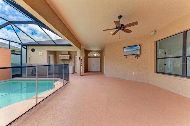 view of swimming pool with a patio area, ceiling fan, and glass enclosure