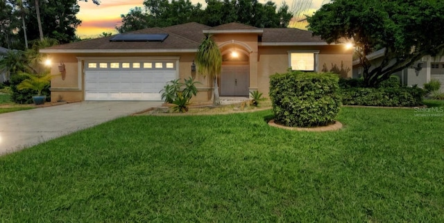 view of front facade with a garage, a yard, and solar panels