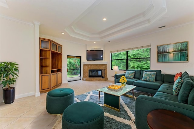 living room with a tile fireplace, plenty of natural light, light tile patterned flooring, and a tray ceiling