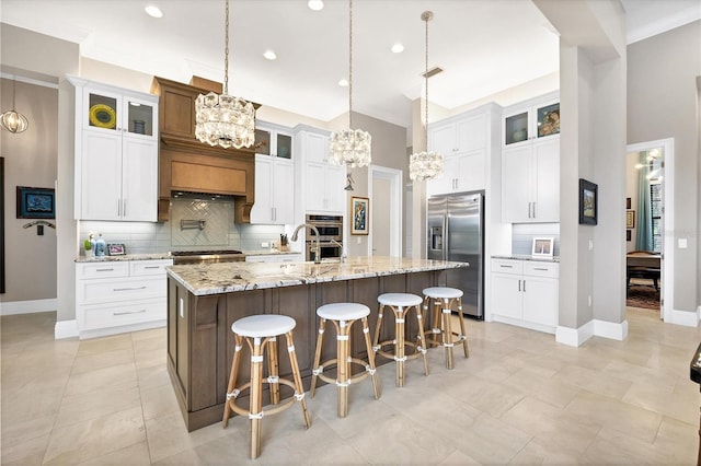 kitchen featuring white cabinetry, an island with sink, stainless steel appliances, a kitchen breakfast bar, and hanging light fixtures