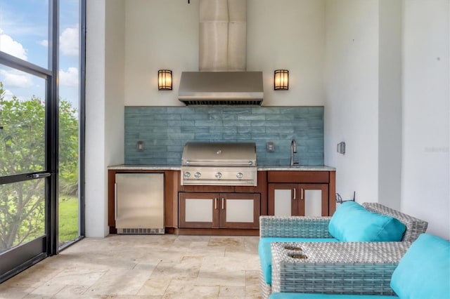 kitchen with wall chimney exhaust hood, stainless steel fridge, tasteful backsplash, and sink