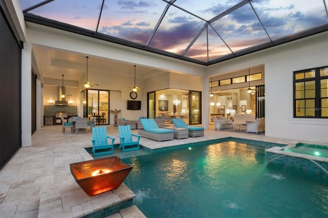 pool at dusk with a lanai, ceiling fan, pool water feature, and a patio