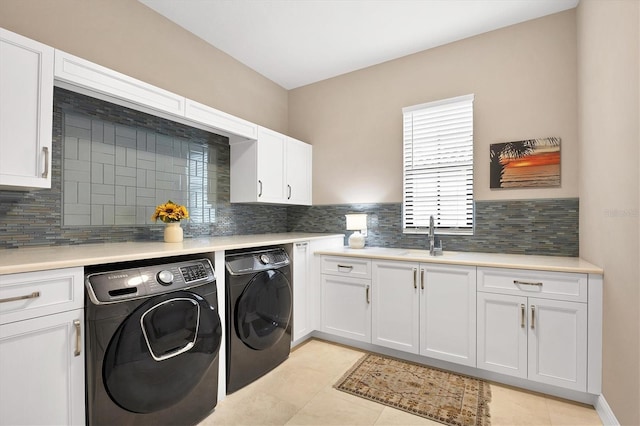 laundry area with cabinets, light tile patterned floors, washing machine and clothes dryer, and sink