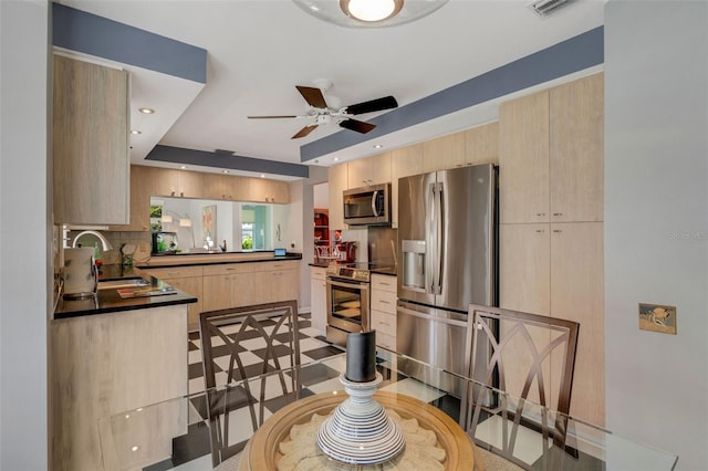 kitchen with backsplash, sink, ceiling fan, appliances with stainless steel finishes, and light brown cabinets