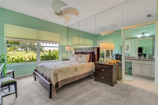 bedroom with light wood-type flooring, ceiling fan, connected bathroom, and sink