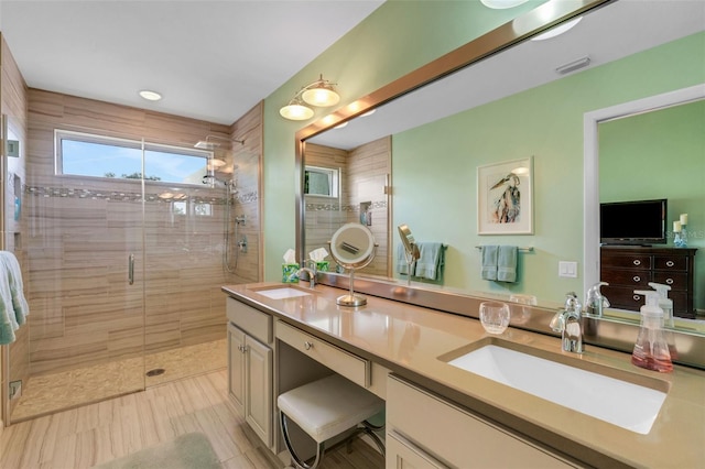 bathroom featuring a shower with door and vanity