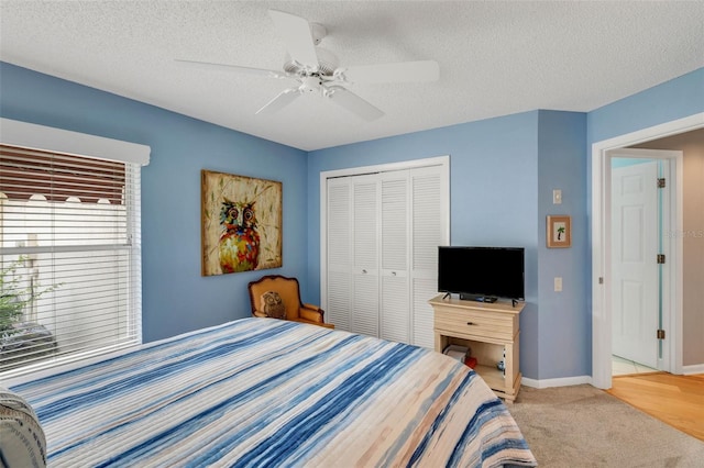 bedroom featuring light hardwood / wood-style flooring, a closet, ceiling fan, and a textured ceiling