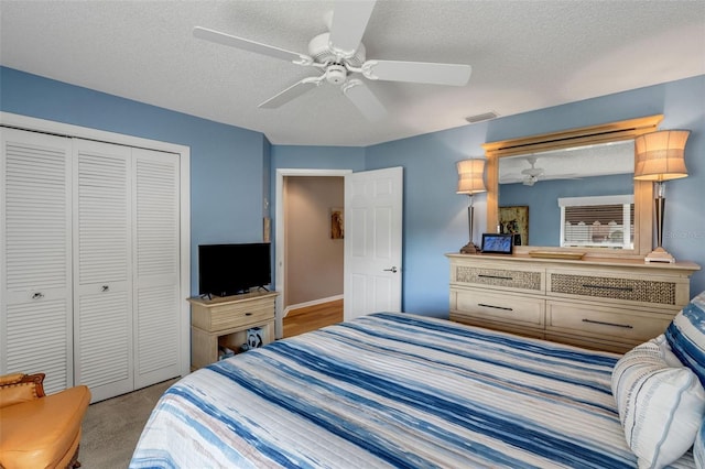 bedroom with light colored carpet, a textured ceiling, ceiling fan, and a closet