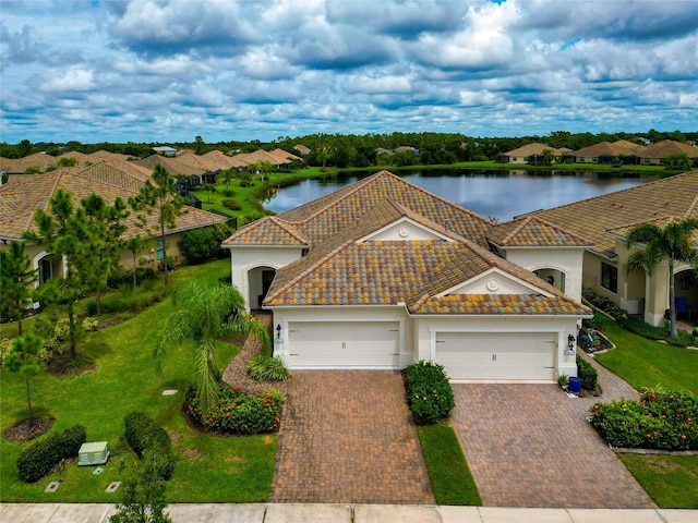 mediterranean / spanish home with a garage, a water view, and a front lawn