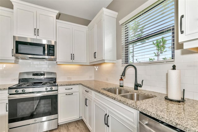 kitchen featuring appliances with stainless steel finishes, light hardwood / wood-style floors, sink, decorative backsplash, and white cabinets