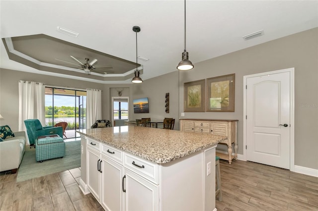 kitchen with white cabinets, light hardwood / wood-style floors, a raised ceiling, and ceiling fan