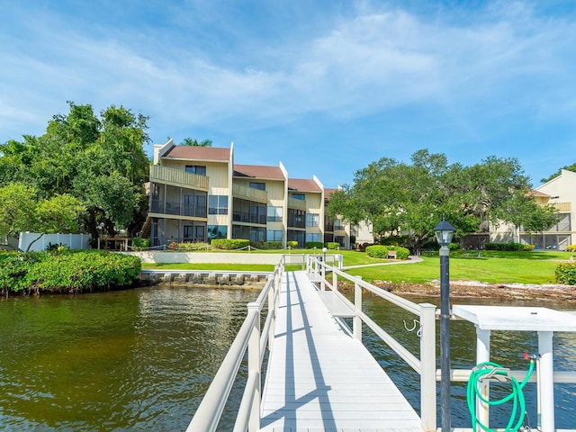 dock area with a lawn, a water view, and a balcony