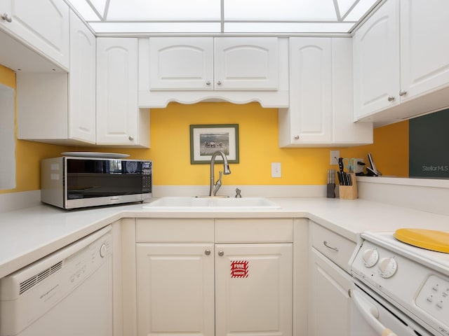 kitchen featuring white appliances, white cabinetry, and sink