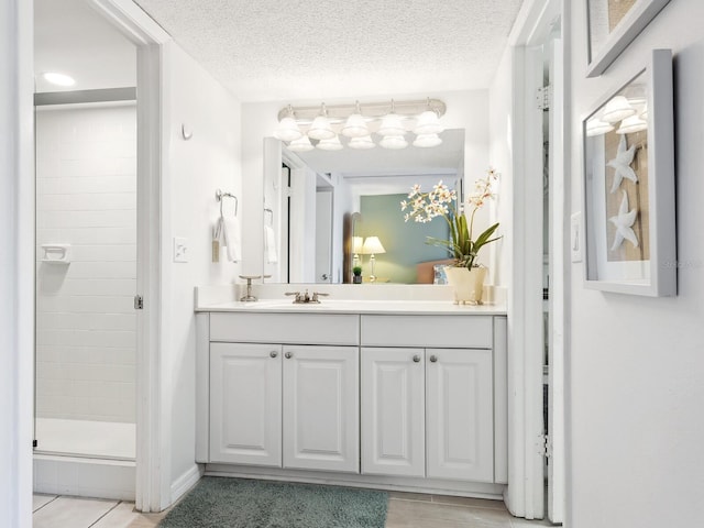 bathroom with vanity, a textured ceiling, and a shower with door