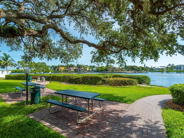 surrounding community with a lawn, a water view, and a patio area