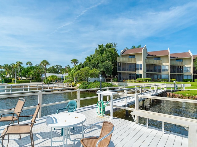 view of dock with a balcony, a water view, and a yard