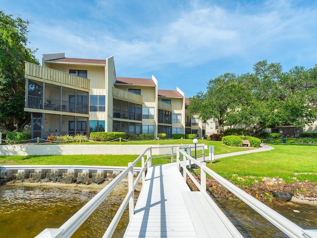 exterior space with a balcony, a yard, and a water view