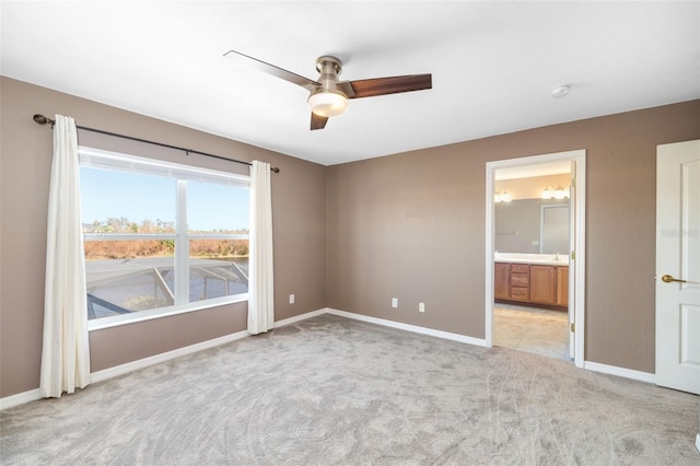 unfurnished bedroom featuring ensuite bath, light carpet, and ceiling fan