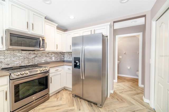 kitchen featuring white cabinetry, light parquet floors, stainless steel appliances, and backsplash