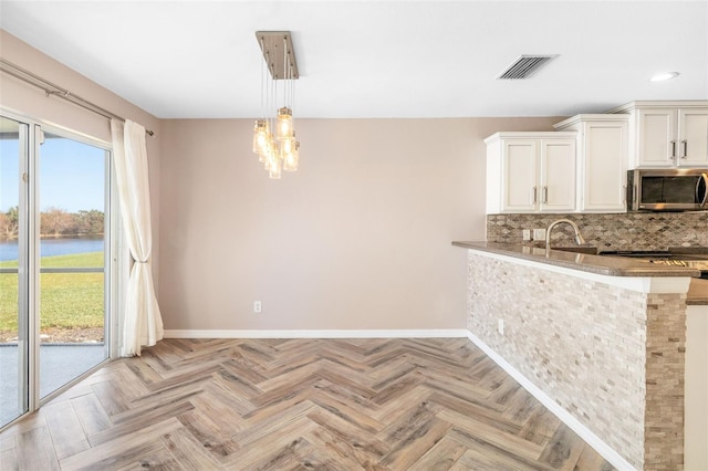 kitchen with light parquet floors, tasteful backsplash, kitchen peninsula, and hanging light fixtures