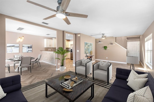 living room with light parquet floors and ceiling fan with notable chandelier