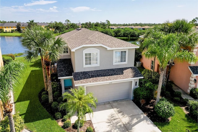 view of front facade with central AC, a garage, a front yard, and a water view