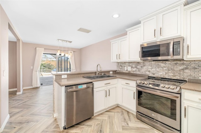 kitchen featuring kitchen peninsula, stainless steel appliances, sink, white cabinets, and tasteful backsplash