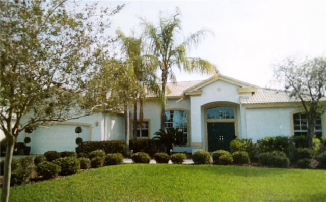 mediterranean / spanish-style house with a front yard and a garage