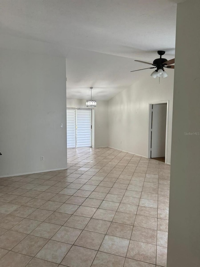 tiled spare room with ceiling fan with notable chandelier