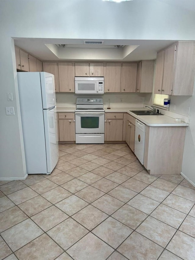 kitchen featuring light brown cabinets, a raised ceiling, sink, and white appliances