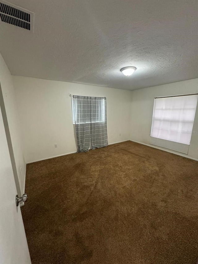 carpeted spare room with a textured ceiling