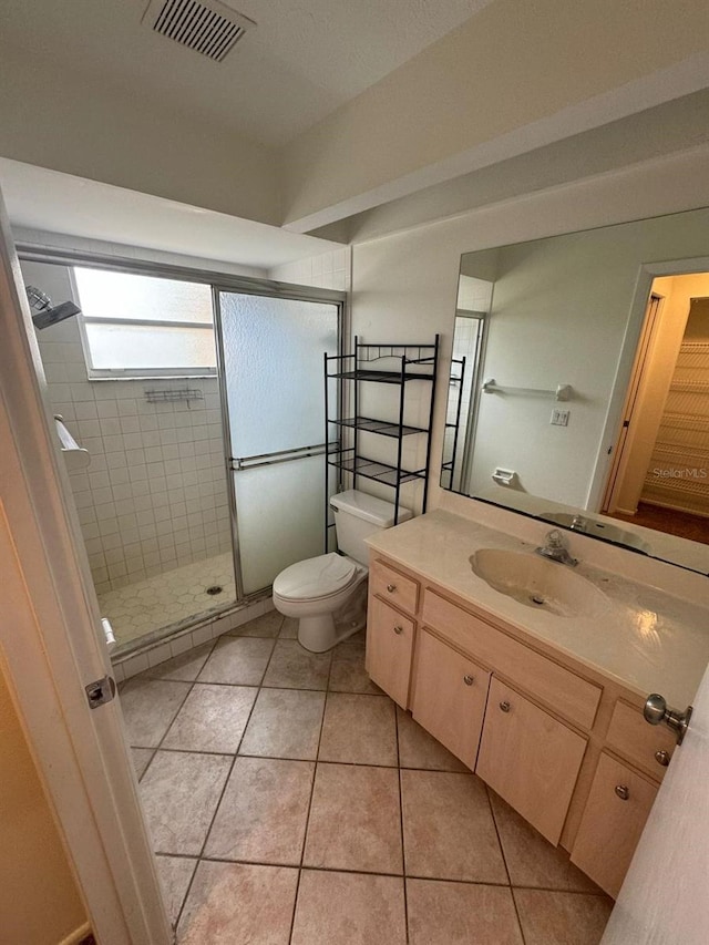 bathroom featuring walk in shower, vanity, tile patterned flooring, and toilet