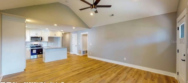 kitchen featuring appliances with stainless steel finishes, tasteful backsplash, white cabinetry, light stone countertops, and light hardwood / wood-style flooring