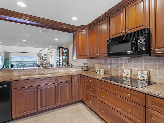 kitchen with light stone countertops, sink, and black appliances