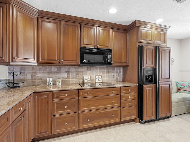 kitchen with light stone countertops, backsplash, and black appliances