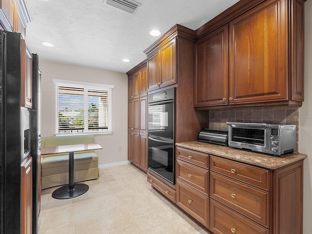 kitchen with stone counters, double oven, and backsplash