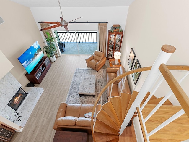 living room featuring ceiling fan, a high end fireplace, a towering ceiling, and hardwood / wood-style floors