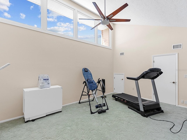 workout area featuring light carpet, ceiling fan, a textured ceiling, and high vaulted ceiling