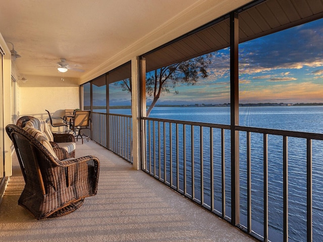 sunroom / solarium featuring a water view and ceiling fan