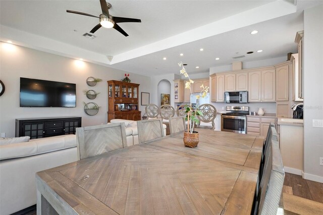 dining area with visible vents, a tray ceiling, recessed lighting, wood finished floors, and arched walkways