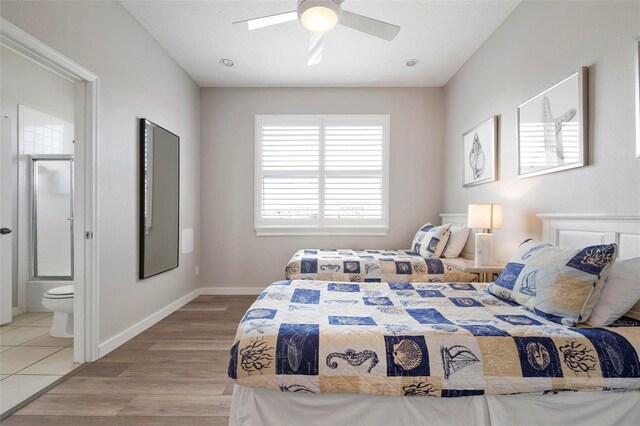 bedroom with light wood-style flooring, a ceiling fan, baseboards, and ensuite bathroom