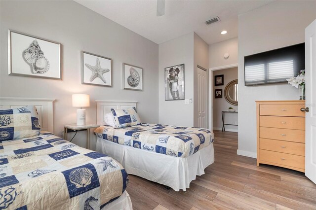 bedroom featuring visible vents, baseboards, wood finished floors, and a ceiling fan