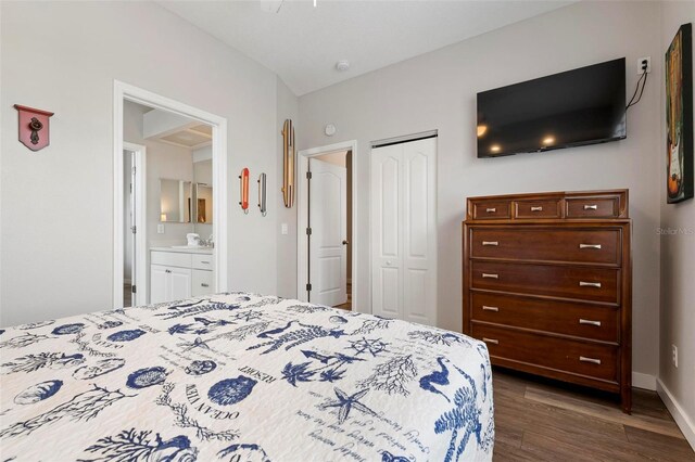 bedroom featuring a closet, dark wood-type flooring, baseboards, and a sink