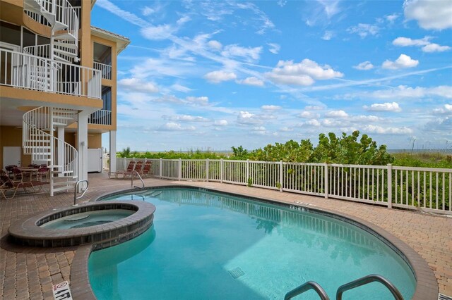 view of swimming pool with stairway, a patio area, fence, and a pool with connected hot tub