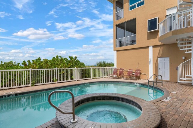 community pool featuring a patio area, fence, and a hot tub